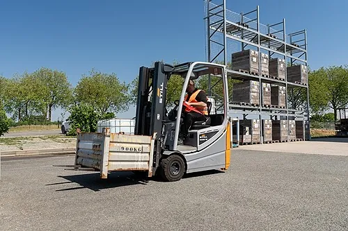 Conducteur en formation sur un chariot élévateur R489, charge levée en extérieur