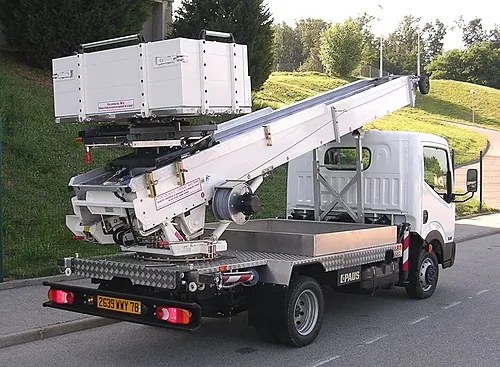 Monte-meubles monté sur un camion, flèche relevée et plateau de chargement en tête